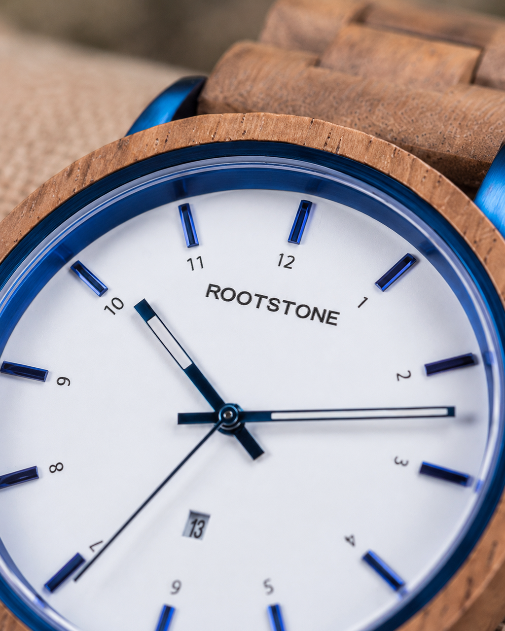 Close-up des weißen Zifferblatts der Rootstone BLÅSKOG Herrenuhr mit blauen Indizes, Zeigern und Datumsanzeige
